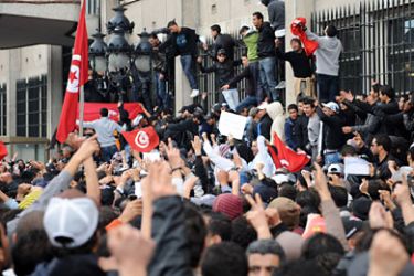Tunisian demonstrators, some standing on the windowsills and main door of the Interior ministry in Tunis, on January 14, 2011, rally demanding President Zine El Abidine Ben Ali's resignation. Thousands of protesters demanded President Zine El Abidine Ben Ali resign in marches across the country on January 14,