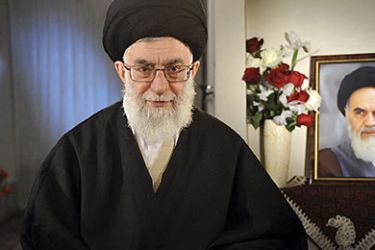 Iran's Supreme Leader Ayatollah Ali Khamenei sits next to a portrait of late leader Ayatollah Ruhollah Khomeini while taking part in a live television programme in Tehran on the occasion of the Iranian New Year March 21, 2011.