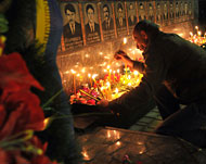 أوكراني يشعل شمعة أمام صور ضحايا حريق تشرنوبيل (الفرنسية)