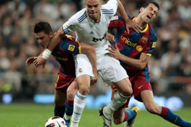 Real Madrid's Pepe (C) is challenged by Barcelona's David Villa (L) and Sergio Busquets during their Spanish first division soccer match at Santiago Bernabeu stadium in Madrid, April 16, 2011.