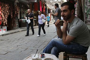tourist shop owner sipping his tea outside his store in the bazaar of Damascus' Old City. Tourists have deserted the warren of ancient alleyways of the Syrian capital and merchants sit forlornly in front of their shops, killing time playing backgammon, fiddling with worry beads or discussing the unrest roiling