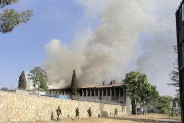 Afghan National Army soldiers walk towards smoke rising from a fire in a government building, where Taliban insurgents who have taken over the building are fighting NATO and Afghan forces, in Khost province May 22, 2011. Three policemen were killed and three others wounded when four Taliban insurgents, including suicide bombers, attacked a government building in Afghanistan's eastern Khost province, a senior police official said. REUTERS