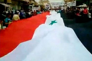 Crowds carry a huge Syria flag during a protest in Al-Qamishly May 6, 2011 in this still image taken from video uploaded on a social media website. Syrian security forces killed 22 protesters on Friday demanding an end to President Bashar al-Assad's rule, rights campaigners said, and the European Union agreed to impose sanctions in response to his crackdown.