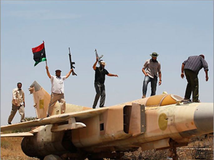 Libyan rebel fighters stand on top of a fighter plane belonging to forces loyal to Muammar Gaddafi during a patrol at Misrata's airport May 28, 2011.