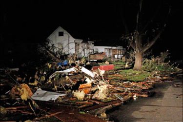 r : Scattered debris surrounds a damaged home in a neighborhood hard hit by a devastating tornado in Joplin, Missouri May 23, 2011. Tornadoes tore through parts of the U.S. Midwest on Sunday, killing at least 30 people in Joplin,