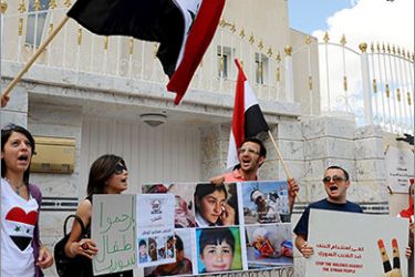 Tunisian and Syrian protesters hold photos, signs, and Syrian flags during a demonstration against Syria's strongman Bashar al-Assad, in front of the Syrian embassy in Tunis, on June 11, 2011. AFP PHOTO / FETHI BELAID