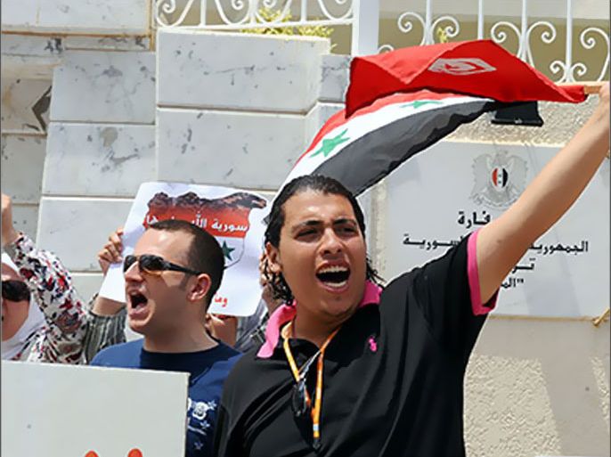Tunisian and Syrian protesters hold signs, and wave Tunisian and Syrian flags side by side during a demonstration against Syria's strongman Bashar al-Assad, in front of the Syrian embassy in Tunis, on June 11, 2011. AFP PHOTO / FETHI BELAID