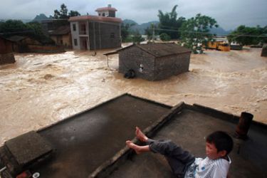 A young boy watches the flood waters from the roof of his home in Laibin, southwest China's Guangxi province on June 16, 2011.
