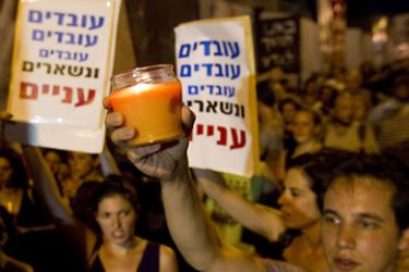 Israelis hold-up signs that read, "work, work, work, you stay poor" as they march in the centre of Tel Aviv on July 25, 2011, to protest against rising housing prices and social inequalities in the Jewish state.
