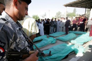 An Iraqi policeman stands beside the bodies of those who were killed by gunmen at a hospital morgue in Kerbala, 80 km (50 miles) southwest of Baghdad, September 13, 2011. Gunmen killed 22 Iraqi Shi'ite pilgrims in an ambush in the Sunni heartland province of Anbar on Monday, a police official said.