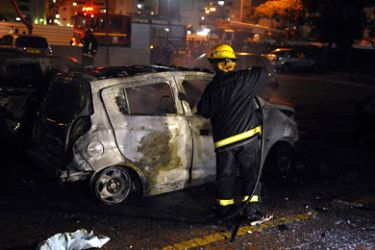 An Israeli fire fighter checks a burnt out car after rockets launched from the Palestinian Gaza Strip landed in the coastal Israeli city of Ashdod on October 29, 2011,