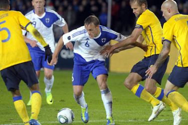 ف-Finland's Mika V&auml;yrynen (C) controlls the ball in between Sweden's Martin Olsson (L), Olof Mellberg