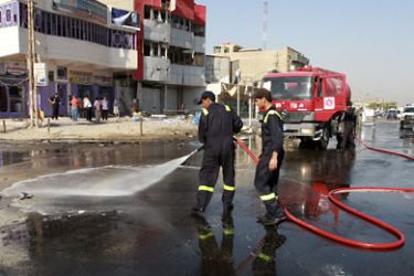 r_Firefighters wash the site of a car bomb attack that targeted a police patrol in the southern Ilaam district of Baghdad October 12, 2011. Two suicide car bombers and a car bomb hit police