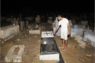 A man looks at tombstones which were vandalized at two cemeteries belonging to Muslims and Christians daubed with the messages “Death to Arabs” and “Price tag” after they were spray painted on the graves in the Arab city of Jaffa, near Tel Aviv, on October 8, 2011. AFP PHOTO/AHMAD GHARABLI