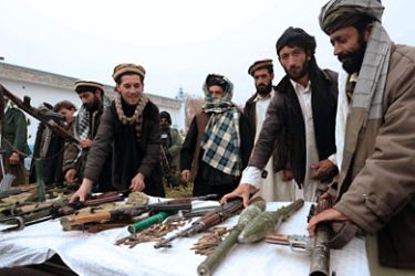Taliban fighters stand near their weapons after they joined Afghanistan government forces during a ceremony in Herat on November 27, 2011. Twelve fighters left the Taliban to join the government in western Afghanistan