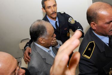 Baghdadi al-Mahmudi (C), Libya's premier until the final weeks of Moamer Kadhafi's regime puts his hands on his face as he arrives in court, escorted by police, on November 8, 2011 in Tunis . Mahmudi was arrested on September 21 on Tunisia's southwestern border with Algeria under a warrant from the new authorities in Tripoli. A Tunisian judge examines on November 8 a request from Libya for his extradition-