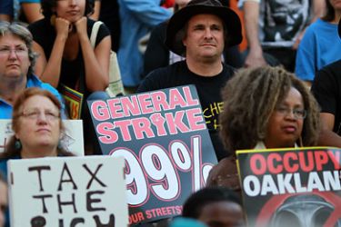 California, UNITED STATES : OAKLAND, CA - NOVEMBER 02: Protestors hold signs as they demonstrate during Occupy Oakland's general strike on November 2, 2011 in Oakland, California