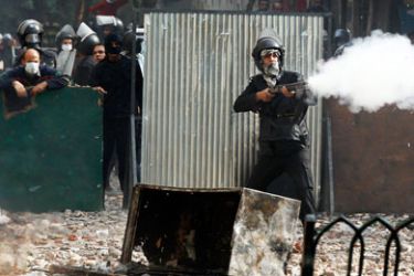 A riot policeman fires a shotgun at protesters during clashes at a side street near Tahrir Square in Cairo November 23, 2011.