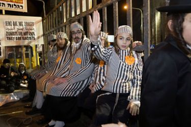 Group of ultra-Orthodox Jews wearing prison uniforms from the Holocaust and yellow Stars of David with 'Jude' written on them sit in a truck with bars during a demonstration in Jerusalem's Mea Shearim neighborhood, on December 31, 2011 to protest against what they call the 'media campaign of incitement'