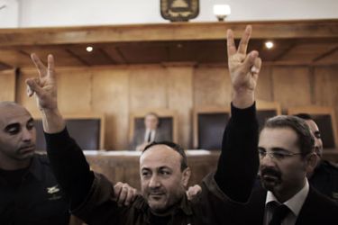Palestinian Fatah leader Marwan Barghuti flashes the V-sign of victory as he is escorted by Israeli police into Jerusalem's Magistrate Court to testify as part of a US civil lawsuit against the Palestinian leadership, on January 25, 2012