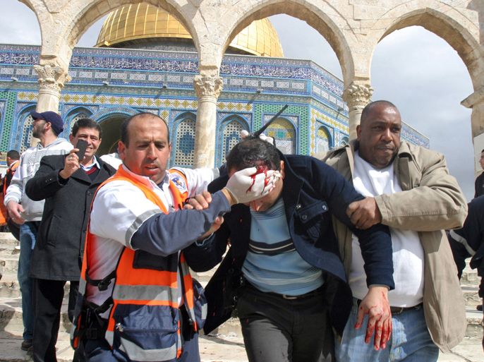 epa03119768 A Palestinian medic and a civilian assist a Palestinian man bleeding from his head as they remove him from near the Dome of the Rock, behind, during running clashes between Palestinians and Israeli security forces following noon prayers at al-Aqsa Mosque on the Temple Mount, or Hareem el-Sharif, Jerusalem, 24 February 2012.