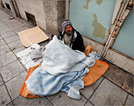 أحد المشردين بمدينة نيس بفرنسا يحتمي ببطانية من البرد (رويترز)