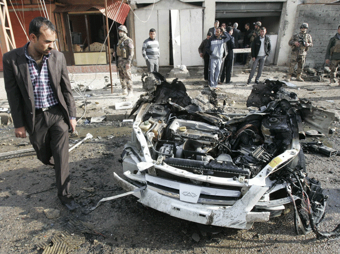 A man walks past the remains of a vehicle used in a bomb attack in Kirkuk, 250 km (155 miles) north of Baghdad February 23, 2012. Two car bombs exploded in a quick succession in different districts wounding 20 people, including 15 policemen, in Kirkuk, police said. REUTERS/Ako Rasheed (IRAQ - Tags: CIVIL UNREST)