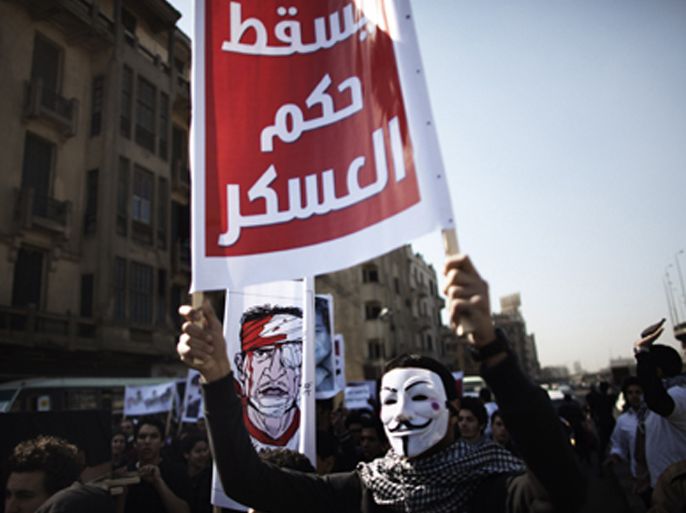An Egyptian student wearing a V for Vendetta Guy Fawkes mask which is the symbolic mask of Occupy protesters holds an Arabic slogan which reads "Down with the military rule" during a protest against the military rulers of the country in Cairo on February 11, 2012.