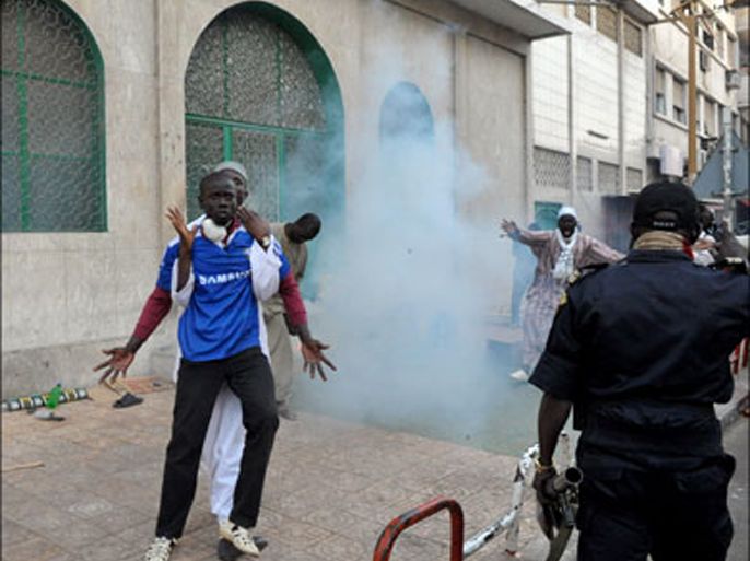afp : A Senegalese policemanstands beside gesturing protestors on Feburary 17, 2012 in Dakar during a demonstration against President Abdoulaye Wade's third term bid. Burning debris and rocks littered the streets around Independence Square as riot police on trucks and foot chased protesters to prevent them from converging, firing volleys of tear gas throughout the afternoon. AFP PHOTO / SEYLLOU
