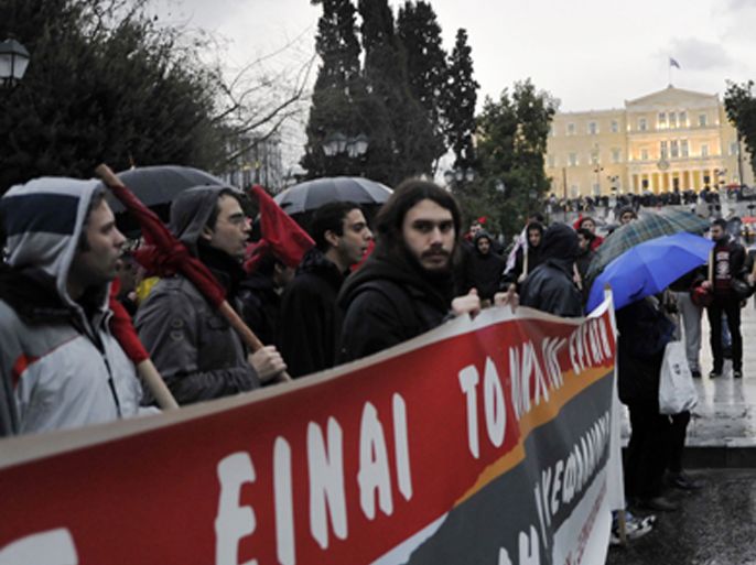 Communist party affiliated protesters march under the rain during a demonstration against new austerity measures in front of the Greek parliament in Athens on February 22, 2012. Greek unions staged new protests as parliament prepares to debate a draft bill needed to secure an unprecedented eurozone bailout and debt swap.