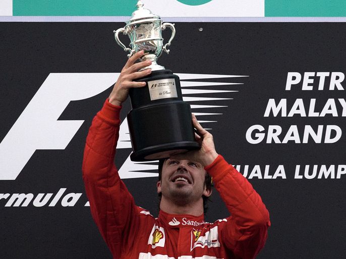 Ferrari driver Fernando Alonso (C) of Spain lifts his winning trophy during the ceremony of Formula One's Malaysia Grand Prix at the Sepang International Circuit in Sepang on March 25, 2012.