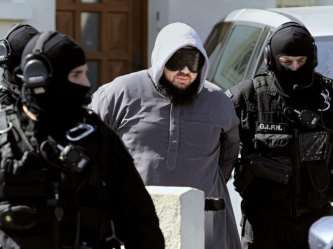 French members of the French National Police Intervention Group (GIPN) arrest Forsane Alizza Islamic radical group's leader Mohamed Achamlane after searching his house in Bouguenais, western France, on March 30, 2012 as part of down raids in several French cities. French police arrested 19 people in a crackdown on suspected Islamist networks as President Nicolas Sarkozy made the battle against extremism the keynote of his re-election campaign. AFP