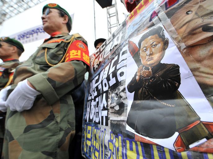South Korean veterans stand next to a placard showing a caricature of North Korean leader Kim Jong-Un during an anti-North Korea rally to mark the 2nd anniversary of the sunking of the South Korean naval ship Cheonan, which was sunk near the maritime border with North Korea in March 2010, in Seoul on March 16, 2012