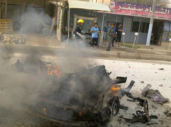 A fireman runs behind the burning carcass of a car following two car bombs explosions in the Iraqi city of Ramadi in the western Anbar province on April 19, 2012, as a wave of bombings and shootings across Iraq killed more than 35 people and wounded dozens more.