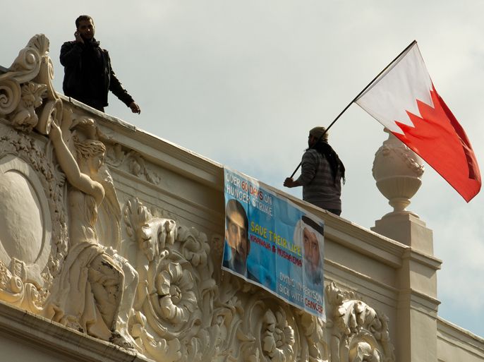 A man waves a Bahraini national flag from the top of the Bahraini Embassy in central London on April 16, 2012 during a protest over the imprisonment of political activist Abdulhadi al-Khawaja who is on hunger strike. Khawaja, a Shiite with dual Danish and Bahraini nationality, has been on hunger strike in a Bahrain prison for the last two months and is reportedly weak but still conscious, a top Danish diplomat said on April 11. He was sentenced with other opposition activists to life in jail over an alleged plot to topple the Sunni monarchy during a month-long protest a year ago. AFP