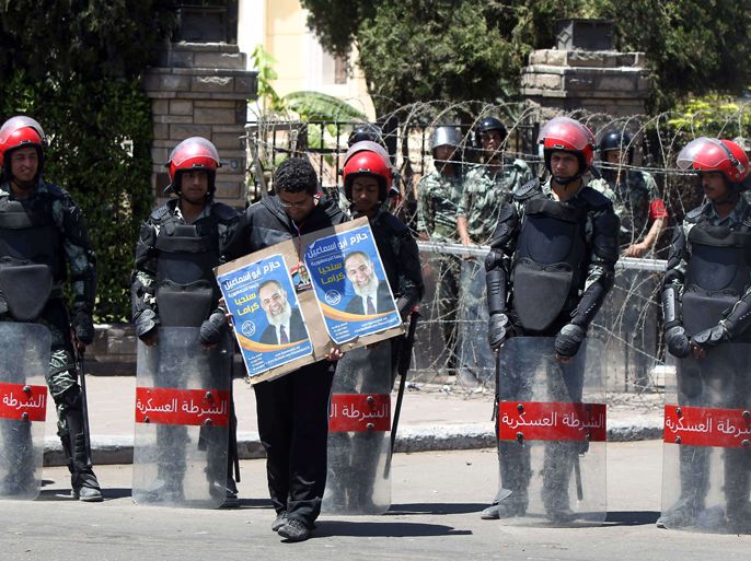 Egyptian military police stand by as a protester holding a placard in support of Salafist presidential candidate Hazem Abu Ismail (portrait) takes part in a demonstration outside the building of the High Presidential Election Committee in Cairo on April 17, 2012. Egypt's political leaders met on April 15, after next month's presidential election was thrown into turmoil with key candidates such as Ismail were disqualified from the presidential race and the fate of a new constitution hangs in limbo. AFP