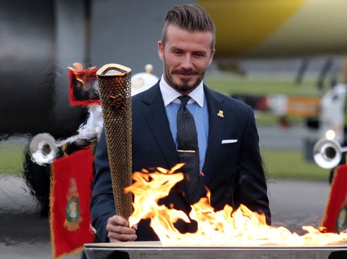 HELSTON, ENGLAND - MAY 18: David Beckham lights the Olympic Flame as it arrives at RNAS Culdrose near Helston on May 18, 2012 in Cornwall, England. The Olympic Flame arrived in the UK after it was handed over at a ceremony yesterday in Athens. A British delegation including David Beckham, flew back with the flame from Greece where they attended a ceremony welcoming the flame, before it is taken on a 70-day relay involving 8,000 torchbearers covering 8,000 miles. (Photo by Matt Cardy/Getty Images)