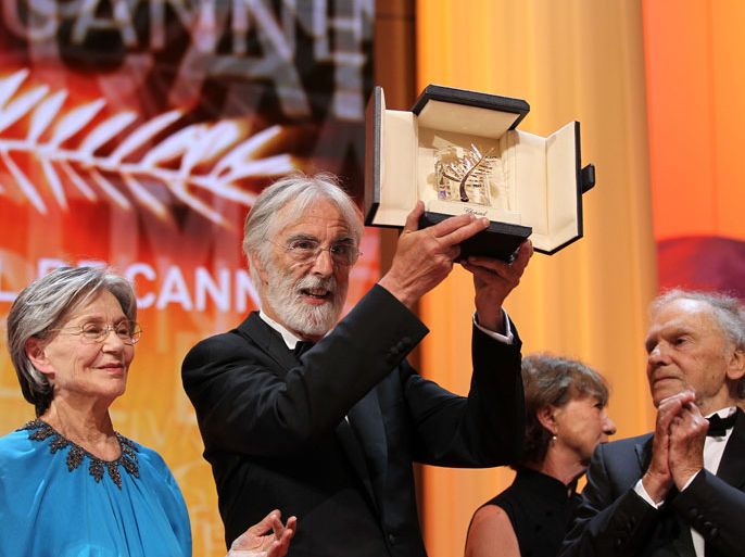 Austrian director Michael Haneke (C) raises his trophy as he poses with French actors Emmanuelle Riva (L) and Jean-Louis Trintignant after being awarded with the Palme d'Or for his film "Amour" during the closing ceremony of the 65th Cannes film festival on May 27, 2012 in Cannes. AFP PHOTO / VALERY HACHE