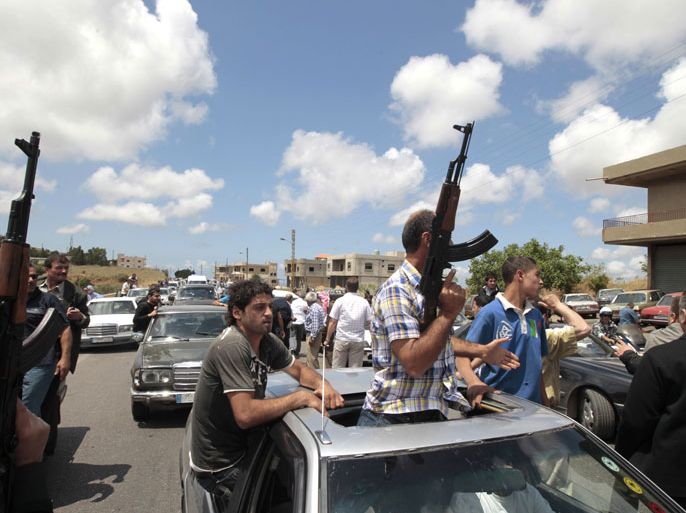 Armed Sunni Muslim men escort the ambulance carrying the body of Sheikh Ahmad Abdel Wahed as it arrives to Amar al-Bakawat at the entrance of his hometown al-Bireh, north of Beirut, for his funeral on May 21, 2012. Wahed was shot dead by army troops when his convoy failed to stop at a checkpoint in the northern Lebanese town of Koueikhat. The incident took place following a week of intermittent