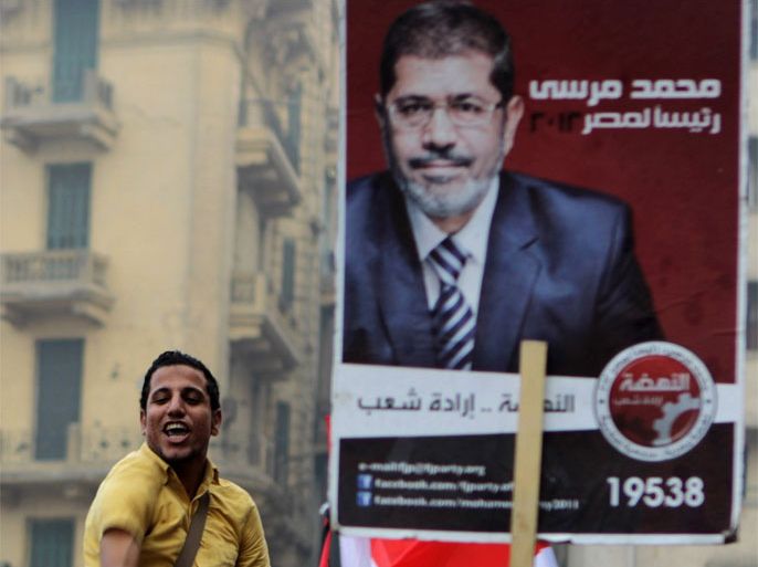 Supporters of Muslim Brotherhood candidate Mohammed Mursi (portrait) celebrate in Cairo's Tahrir square on June 18, 2012 after Islamists claimed victory in Egypt's first free presidential vote since its uprising. Army-backed rival Ahmed Shafiq, who served as prime minister to deposed dictator Hosni Mubarak, disputed the announcement.
