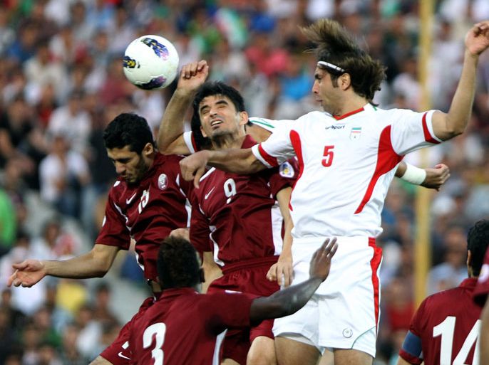Iran's Hadi Aghily (R) heads the ball to score against Qatar's Marcone Junior (C) during their group B, 2014 World Cup Asian qualifying football match, at the Azadi Stadium in Tehran on June 12, 2012. AFP PHOTO/ATTA KENARE