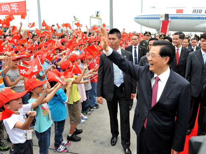 This handout photo taken and received on June 29, 2012 from Hong Kong's Information Services Department shows Chinese President Hu Jintao (R) waving to schoolchildren upon his arrival at Hong Kong's international airport. Hu arrived on June 29 ahead of an inaugaration ceremony for Hong Kong's new government and the 15th anniversary of the southern Chinese city's handover from Britain to China. AFP