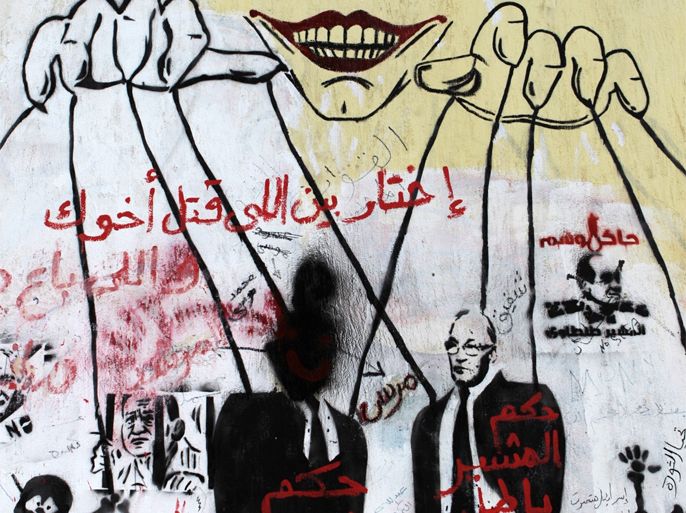 Caption:A graffiti depicting a ruling military puppeteer manipulating Egypt's presidential candidates Ahmed Shafiq (R) and Mohammed Mursi (L) appears on a wall in Tahrir square on June 15, 2012. Egyptian parties and activists have accused the ruling military council of staging a 'counter-revolution,' after a series of measures that consolidated its power ahead of polls to choose a new president.