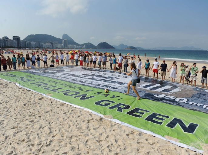 VAN500 - Rio de Janeiro, Rio de Janeiro, BRAZIL : Activist from NRDC (Natural Resources Defense Council), 350.org and Avaaz.org organizations unveil a banner on Copacabana beach to ask world leaders to end fossil fuel subsidies and to "reinvest that money cleanly and greenly", in the framework of the Rio+20 United Nations Conference on Sustainable Development in Rio de Janeiro, Brazil on June 17, 2012, According to them, countries are spending around $1 trillion in subsidies for fossil fuels that are "driving global warming". The UN conference, which marks the 20th anniversary of the Earth Summit -- a landmark 1992 gathering that opened the debate on the future of the planet and its resources -- is the largest ever organized, with 50,000 delegates. AFP PHOTO/VANDERLEI ALMEIDA