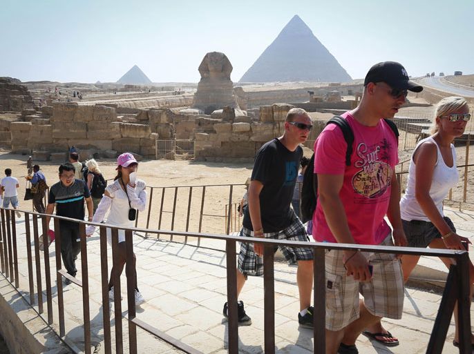 epa03273321 Foreign tourists in front of the great Pyramids in Giza, Egypt, in Cairo, Egypt, 19 June 2012. Tourism accounts for 11.3 per cent of Egypt's gross domestic product, and many of the country's 80 million inhabitants rely on the sector for a living. EPA/JULIEN WARNAND
