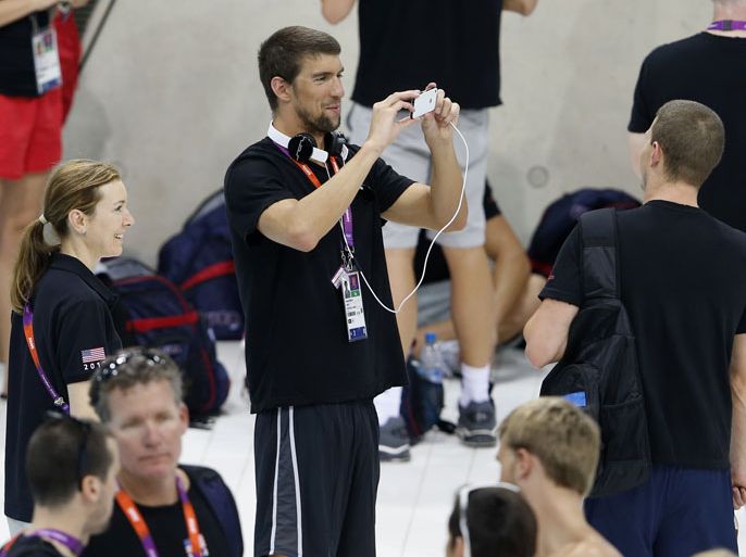 United States' World champion swimmer Michael Phelps takes a picture of a swim team member as the US team arrives for the first training session in the swimming
