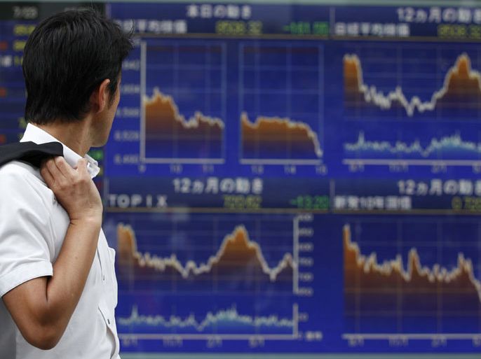 A man looks at an electronic board displaying graphs of various market indices outside a brokerage in Tokyo July 23, 2012. Japan's Nikkei share average posted its biggest fall in a month and a half as it sank to a six-week low on Monday, hit by renewed fears that Spain may need a full-blown bailout and by the subsequent rise in the yen. REUTERS/Yuriko Nakao (JAPAN - Tags: BUSINESS EMPLOYMENT