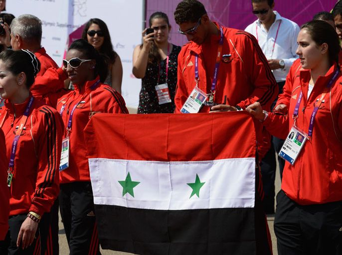 LONDON, ENGLAND - JULY 25: Athletes of Syria hold the Syrian flag as they arrive to attend the official Team welcome ceremony to the Athletes' Village at the Olympic Park on July 25, 2012 in London, England. (Photo by Pascal Le Segretain/Getty Images)