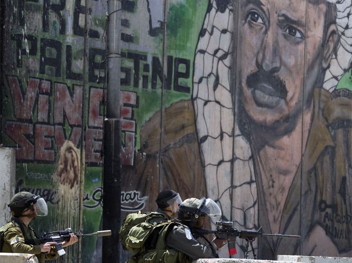 Israeli soldiers take position next to a mural painting of late Palestinian leader Yasser Arafat on Israel's separation barrier at the Qalandia crossing in the occupied West Bank during protests on May 15, 2012, marking Nakba day, which commemorates the exodus of hundreds of thousands of their kin after the establishment of Israel state in 1948.
