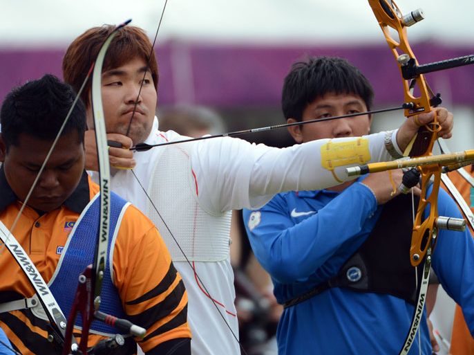 Im Dong-Hyun of South Korea (C) prepares to shoot during the ranking round of the men's archery individual event at the Lord's Cricket Ground in London on July 27, 2012 during the London 2012 Olympic Games. AFP PHOTO / TOSHIFUMI KITAMURA